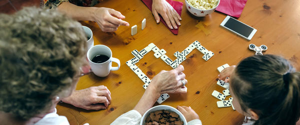 High angle view of family playing dominoes while having food at table