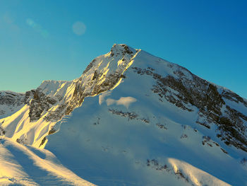 Scenic view of snowcapped mountains against clear blue sky