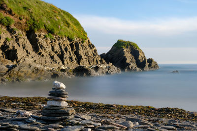 Scenic view of rocks on shore against sky