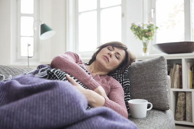 Woman with stomach ache lying on the sofa