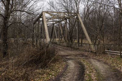 Bare trees on bridge against sky