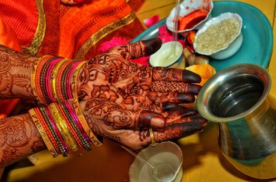 Cropped image of woman with henna tattooed hands performing ritual