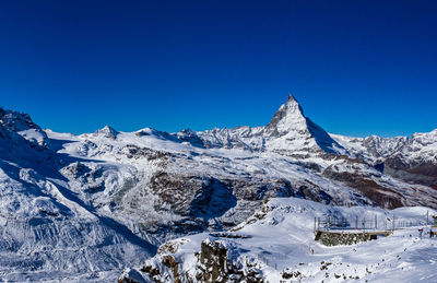 Scenic view of snowcapped mountains against clear blue sky