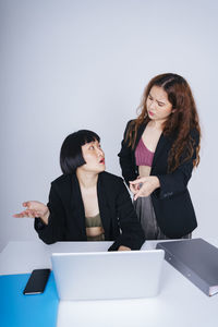 Young woman using phone while sitting on table