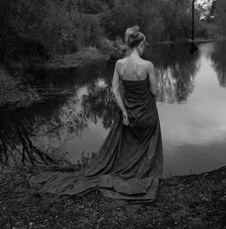 Rear view of woman standing by lake