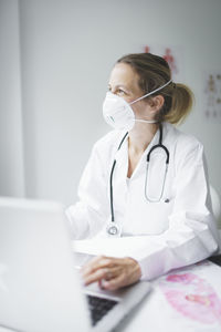 Smiling doctor looking away while sitting at clinic