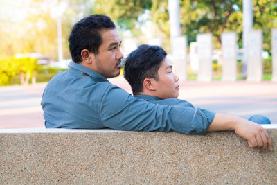 Father and son sitting in park