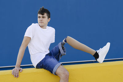 Handicapped teenager sitting on fence