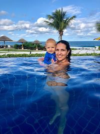 Portrait of smiling woman in swimming pool against sky