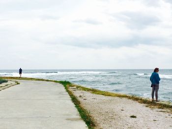 Woman standing at beach against sky