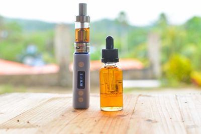 Essential oil in bottle by electronic cigarette on table