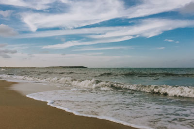 Scenic view of beach against cloudy sky