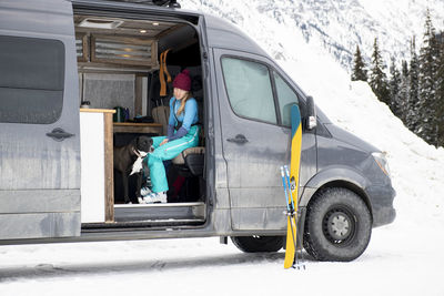 A woman chats with her dog while getting ready for a day of skiing.