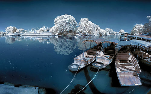 Sailboats moored in lake against sky