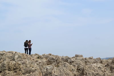 Female friends standing on cliff against sky