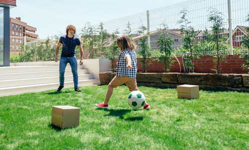 Father and son playing soccer in lawn