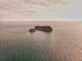 Scenic view of sea against sky and tiny island