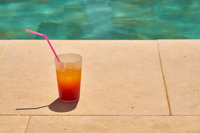 Close-up of drink on table by swimming pool