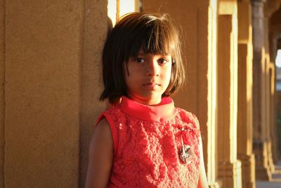 Portrait of girl standing against architectural column