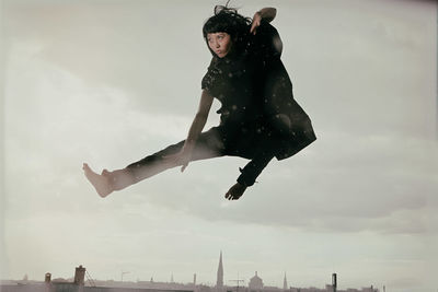 Low angle view of man jumping against sky