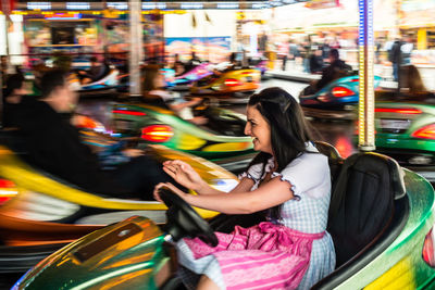 Cheerful woman enjoying in bumper car at amusement park