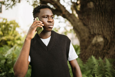 Young man using mobile phone while standing outdoors