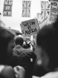 Rear view of crowd protesting on street against buildings