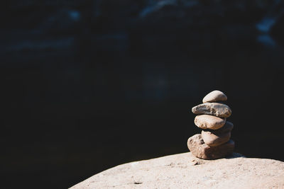 Close-up of stone stack on rock against black background