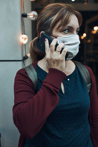 Close-up of woman wearing mask talking on phone outdoors