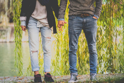 Low section of couple with holding hands standing on grass