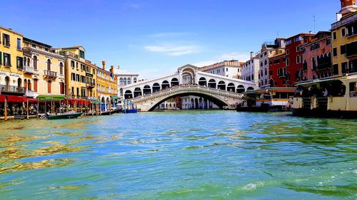 Bridge over canal by buildings against sky