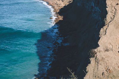A cliff casting shadow over the seashore.