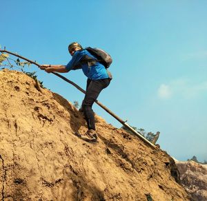 Low angle view of man on rock against sky