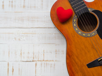 Directly above shot of guitar and heart shape on wooden table