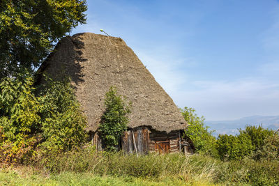 House amidst trees on field against sky