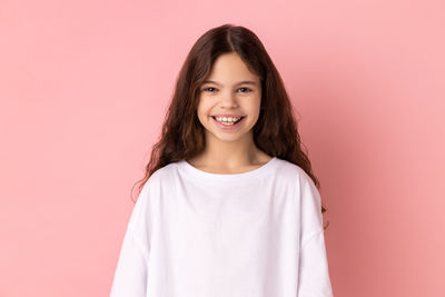 Portrait of young woman against pink background