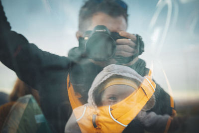 A man with a baby is taking a selfie in a desert of california