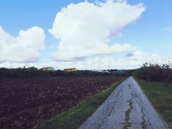 Surface level of road amidst field against sky