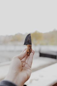 Close-up of hand holding ice cream against sky
