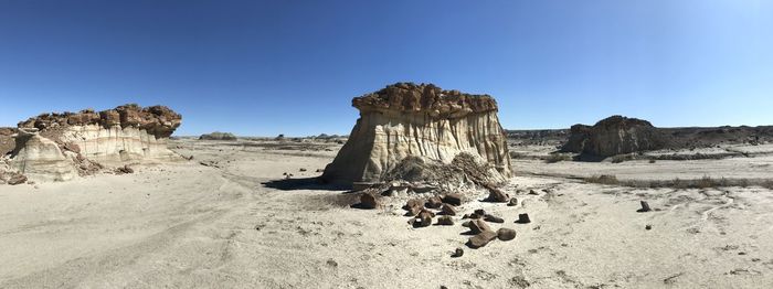 Rock formations on land against clear blue sky