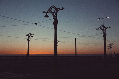 Silhouette fence against sky during sunset