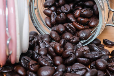 Close-up of coffee beans spilling from jar on table