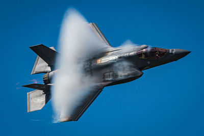 Low angle view of airplane flying against clear blue sky