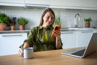 Smiling pleased woman freelance working procrastinating take break, surfing web in mobile phone.