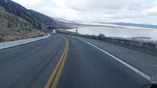 Road by mountains against sky