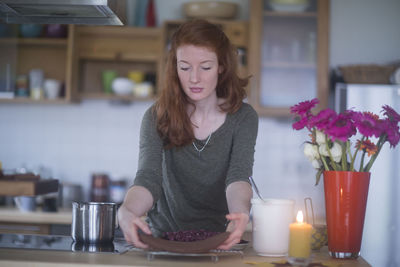 Young woman making birthday cake at home