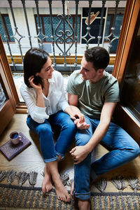 Top view of young intimate couple relaxing next to a window with a balcony at home.