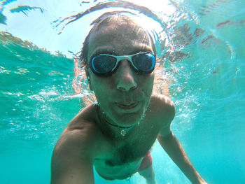 Portrait of shirtless man swimming in pool