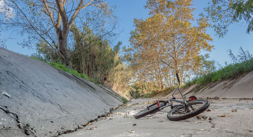 Abandoned bicycle on footpath against sky