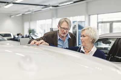 Senior couple examining car in dealership store